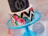 a bold wedding cake with a chalkboard tier and chalking, a chevron tier with floral prints plus a bold bloom on top is amazing
