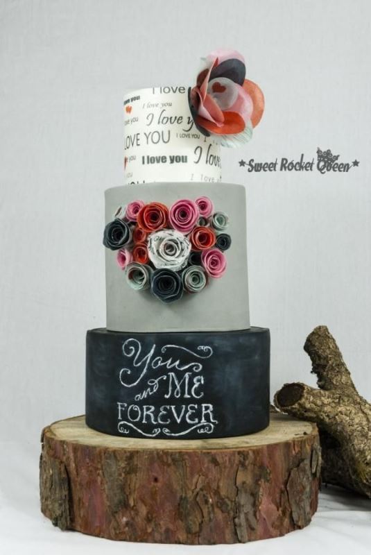 a cool wedding cake with a white, grey and black chalkboard tier, with chalking, quilling flowers and a bold paper one is pure fun
