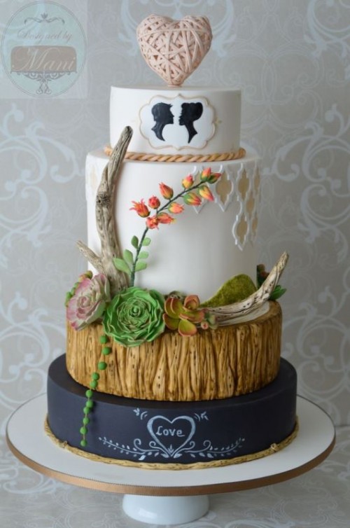 a unique woodland wedding cake with a chalkboard, a wood-inspired tier, white tiers, antlers, blooms, berries and succulents, a yarn heart on top and some silhouettes