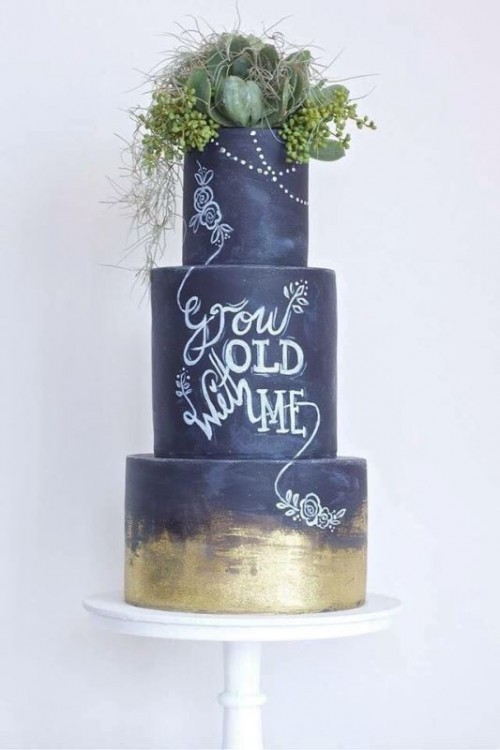 a fantastic chalkboard wedding cake with chalking and gold leaf, with greenery and various succulents on top is fantastic