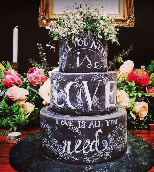 a chalkboard wedding cake with chalking and white blooms on top is a fantastic idea to rock at any wedding