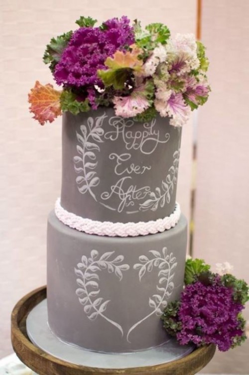 a grey chalkboard wedding cake with chalk detailing and with pastel and other blooms and greenery on top is a gorgeous idea