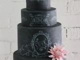 a black chalkboard wedding cake with chalking, pink blooms on it is a unique and creative idea for a modern wedding, with a delicate pink flower touch
