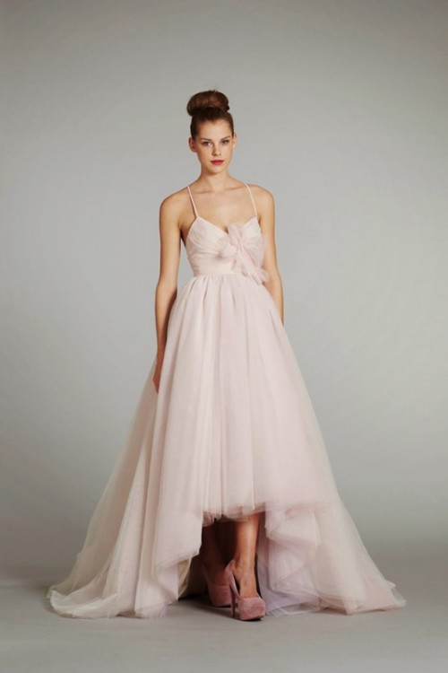 a blush A-line wedding dress with spaghetti straps, a bodice with bows, a layered tulle high low skirt with a train
