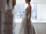 a strapless grey fully embellished A-line wedding dress with a high low skirt and silver shoes for a bold glam bridal look