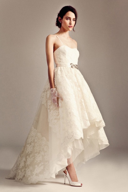 A vintage lace high low wedding dress with a sweetheart neckline and spaghetti straps plus a train and a bow on the sash