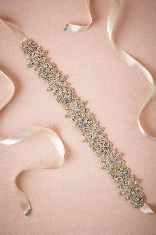 a gold and crystal bridal sash showing different flowers is a chic and bold accessory for a bride that can work with many types of neutral dresses