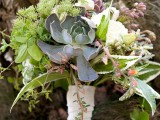 a lush and textural wedding bouquet with lots of greenery, white blooms and succulents plus a a white bouquet wrap for a rustic bride