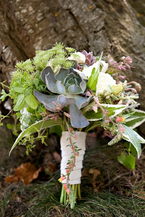 a lush and textural wedding bouquet with lots of greenery, white blooms and succulents plus a a white bouquet wrap for a rustic bride