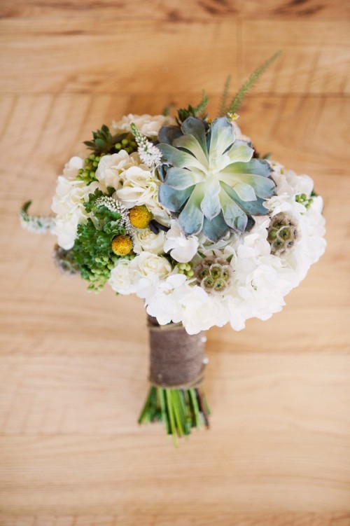 a rustic wedding bouquet composed of white hydrangeas, greenery, succulents and billy balls is a lovely idea for a spring or summer wedding
