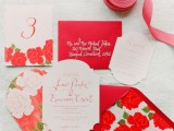 a beautiful wedding invitation suite with red and white floral prints, ribbons and eye-catchily shaped invites and other pieces