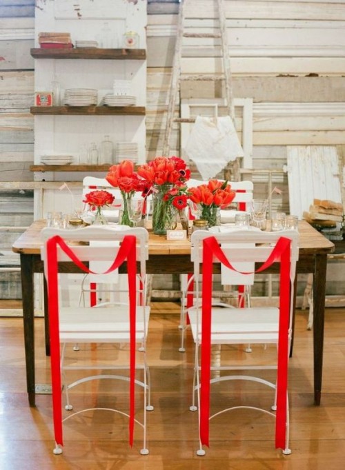 red tulip arrangements and red ribbons on the chairs are a great combo for a modern wedding with red in the color palette