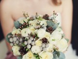 a lovely winter wedding bouquet of white blooms, berries, foliage, waxflower and pinecones is a cute solution with a touch of whimsy
