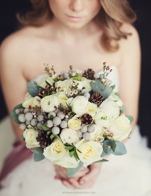 a lovely winter wedding bouquet of white blooms, berries, foliage, waxflower and pinecones is a cute solution with a touch of whimsy