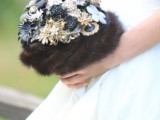 a glam winter wedding bouquet of gold and black brooches, flowers and feathers wrapped with dark faux fur