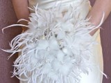 an art deco winter wedding bouquet of white faux blooms with silver brooches and white feathers is a chic and glam idea