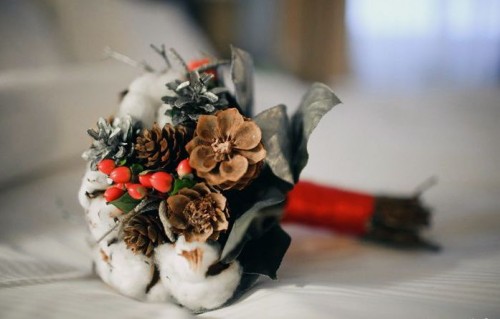 a small Christmassy winter wedding bouquet of pinecones, cotton, berries and silver pinecones plus a red wrap is amazing for holidays