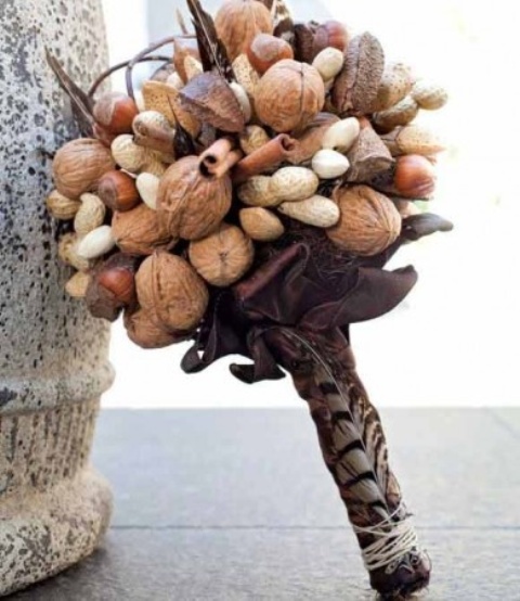 a rustic winter wedding bouquet made of various kinds of nuts, cinnamon sticks, feathers and with a dark wrap will fit a fall wedding, too