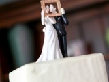 cute bride and groom cake toppers kissing in a frame for a photo is a very fun idea and a creative touch to the wedding cake
