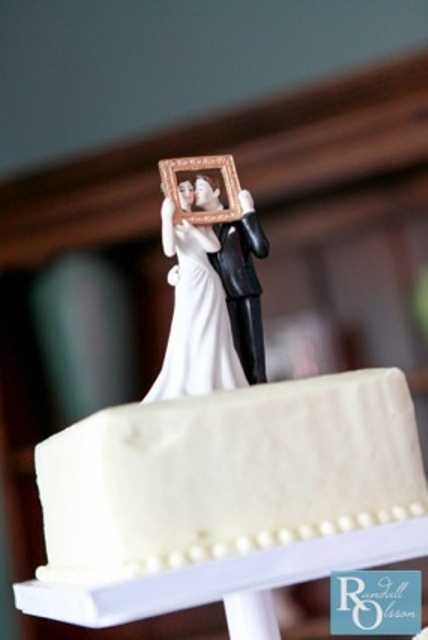 cute bride and groom cake toppers kissing in a frame for a photo is a very fun idea and a creative touch to the wedding cake