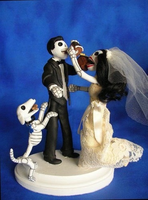 a scary and fun cake topper showing a skeleton couple eating wedding cake together and their skeleton dog is a lovely idea for a themed wedding