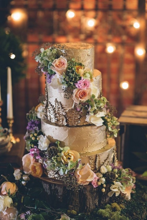 a fantastic woodland wedding cake with textural buttercream, colored blooms, greenery placed on a wood slice