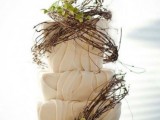 a whimsical woodland wedding cake with textural buttercream, branches, greenery and white blooms on top