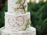 a cute woodland wedding cake that seems to be covered with birch bark, fake branches and a faux nest with birdies on top