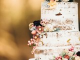 a semi naked wedding cake topped with blooms and berries is a very relaxed and rustic-like idea
