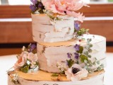 a woodland wedding cake that seems to be made of birch slices, with sugar flowers and greenery