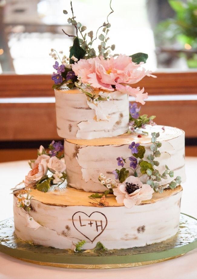 A woodland wedding cake that seems to be made of birch slices, with sugar flowers and greenery