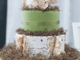 a woodland wedding cake in green and with bark, with hay, moss, a nest with birds topper