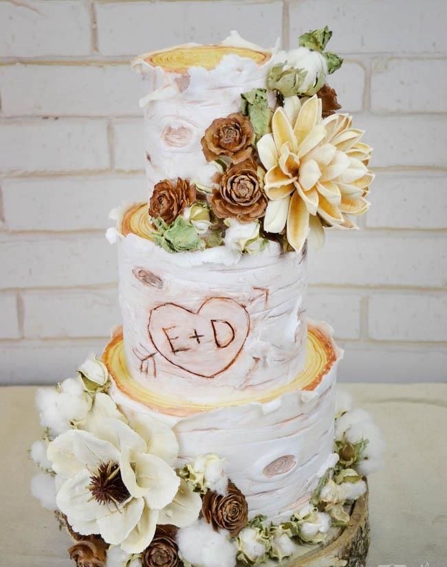 A rustic wedding cake with bark, sugar and real blooms, cotton, greenery