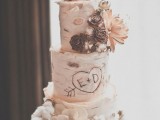 a cozy rustic wedding cake that looks like it’s covered with birch bark, cotton, faux blooms, berries, pinecones and with fun owl toppers