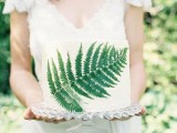 a simple woodland wedding cake in white with a pressed fern leaf for decor is a cute and fresh idea