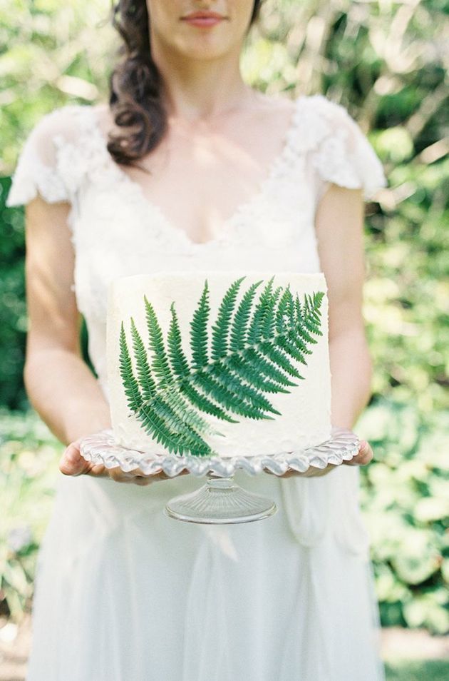 A simple woodland wedding cake in white with a pressed fern leaf for decor is a cute and fresh idea