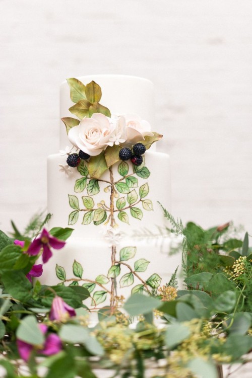 a beautiful handpainted wedding cake with dried foliage, blooms and some fresh berries