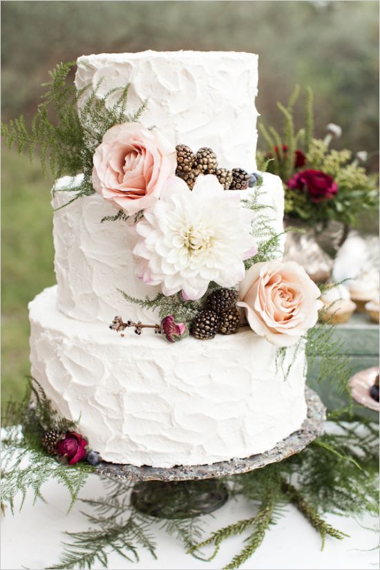 a chic textural buttercream wedding cake topped with fresh blooms and berries plus decorated with ferns