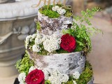 a unique woodland wedding cake that seems to be made of bark, moss and decorated with fresh blooms plus an elegant topper