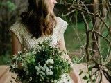 a relaxed boho lace cap sleeve wedding dress with a scoop neckline and a bouquet of wildflowers