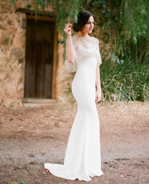 an elegant white mermaid wedding dress with spaghetti straps and an embellished coverup