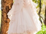 a girlish blush A-line wedding dress with a full skirt, with an embroidered bodice and fabric flowers on the skirt