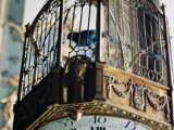 a large vintage cage with a clock on the bottom is a cool wedding decoration idea for a vintage or steampunk wedding