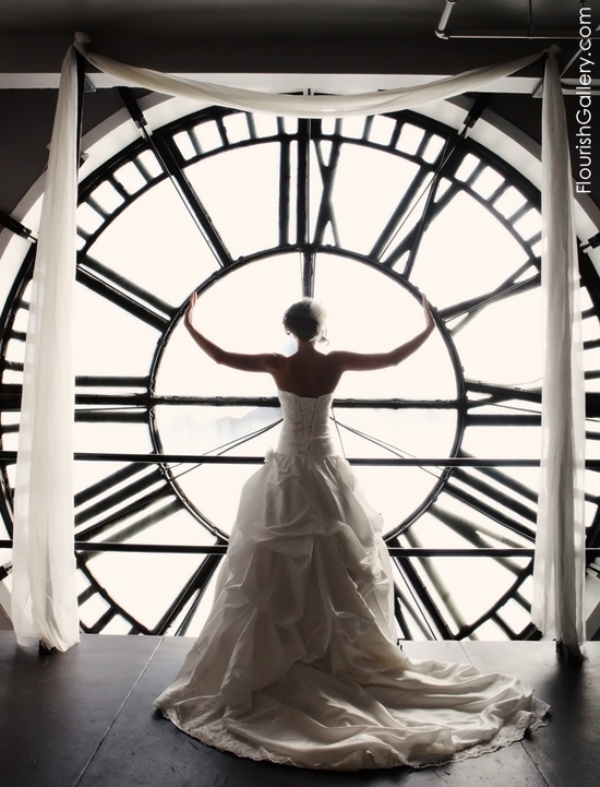 Show off your wedding dress in front of a window with a giant clock, it will be a memorable and bold picture