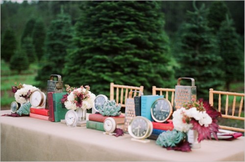 a vintage wedding table decorated with colorful books, clocks, blooms and succulents