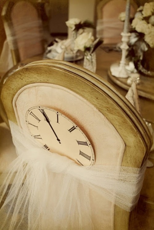 a cardboard clock attached to the chair with tulle is a fun decoration idea for a NYE wedding