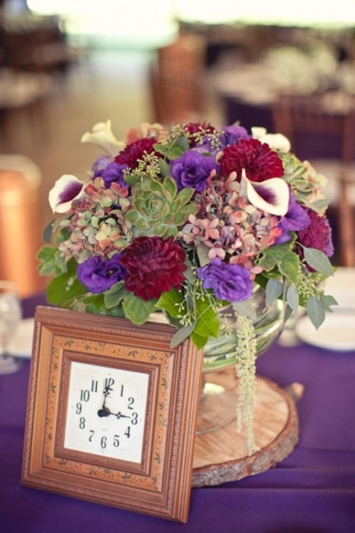 a colorful wedding centerpiece of bright blooms and a clock in a frame for a whimsy vintage wedding reception table