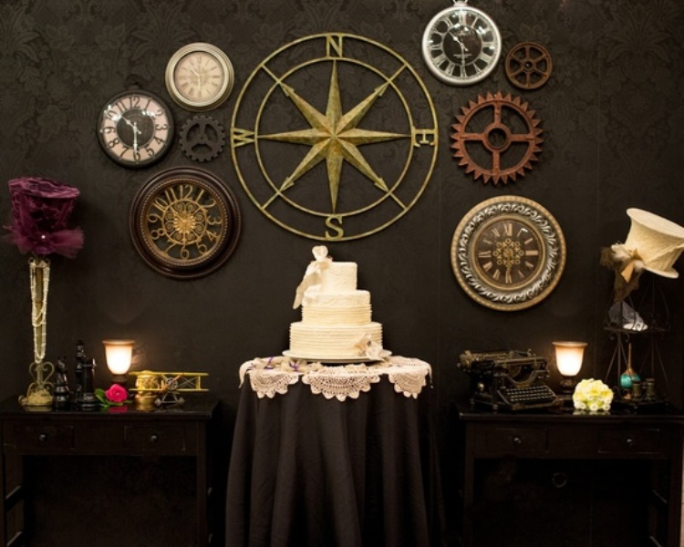a white wedding cake displayed in front of a wall decorated with large gears and clocks is a cool idea