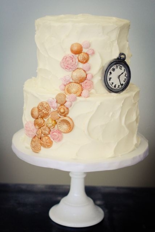 A textural white buttercream wedding cake decorated with pink and gold detailing and an edible clock for fun