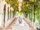 a sophisticated vintage vineyard wedding reception with greenery around, neutral curtains, neutral linens, neutral chair covers and crystal chandeliers